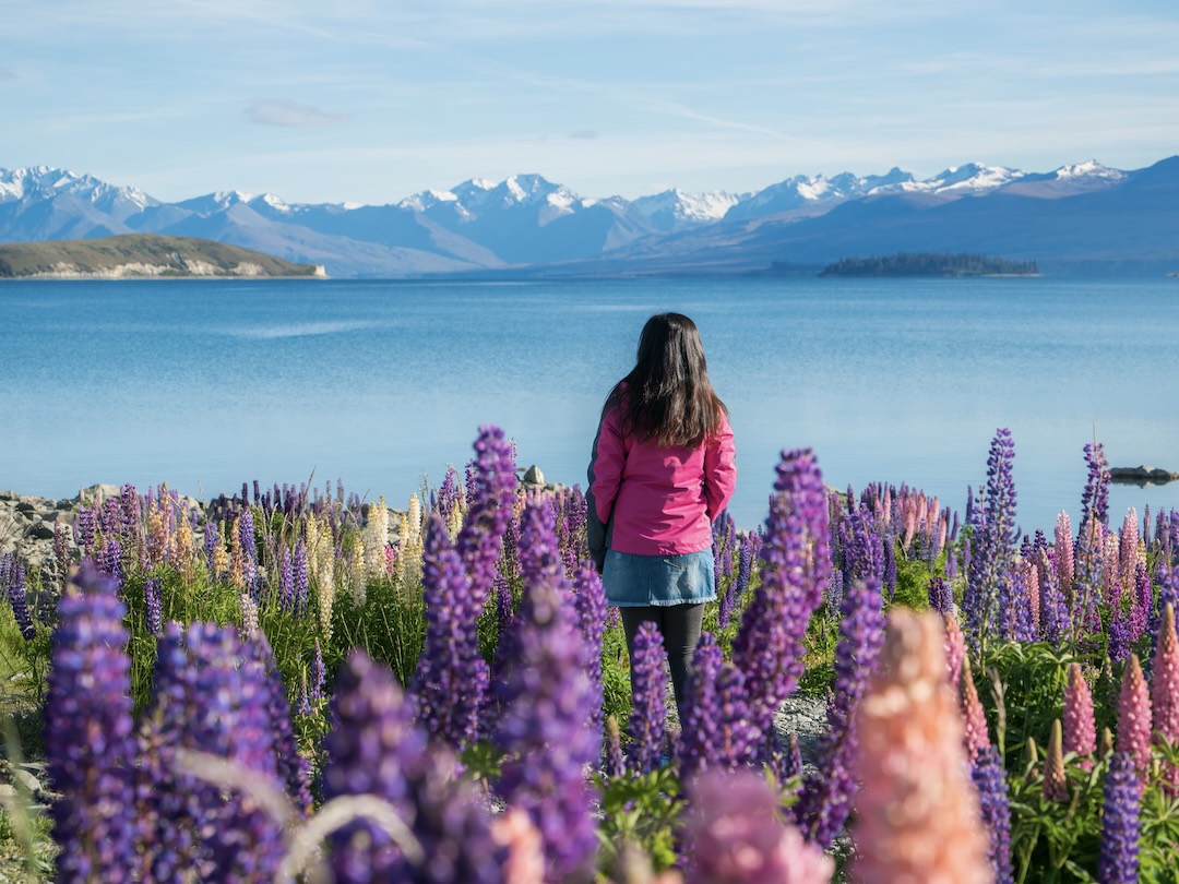 Woman traveller at lake Tekapo during the New Zealand group tour with Other Way Round Travel